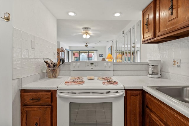 1801 Gulf Dr N Unit 222, Bradenton Beach, FL 34217 - kitchen with white electric range, brown cabinets, a ceiling fan, and light countertops