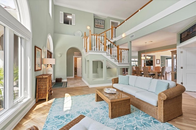 living room featuring a high ceiling, an inviting chandelier, light hardwood / wood-style flooring, and plenty of natural light