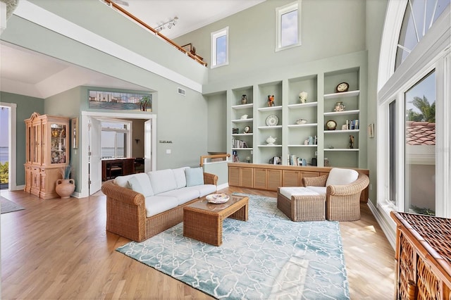 living room with rail lighting, a high ceiling, and light wood-type flooring