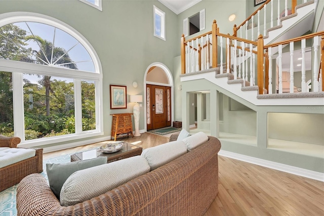 living room featuring a high ceiling, light hardwood / wood-style floors, french doors, and crown molding