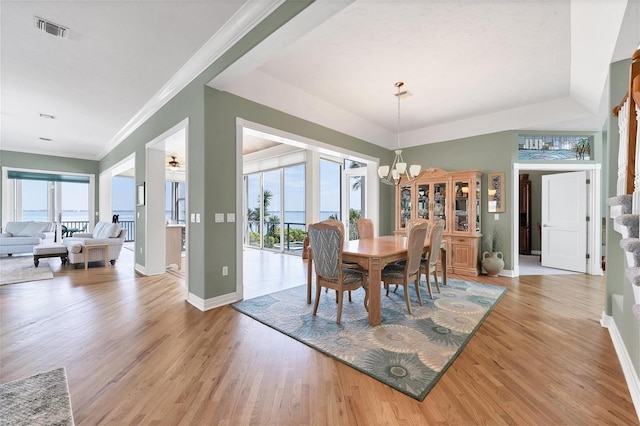 dining area with wood-type flooring, crown molding, and an inviting chandelier