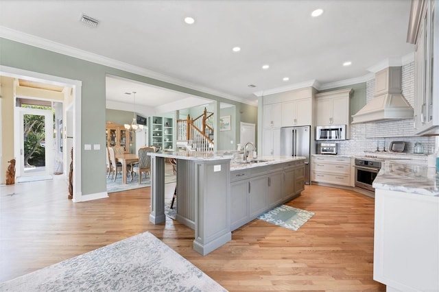 kitchen featuring hanging light fixtures, stainless steel appliances, an inviting chandelier, light hardwood / wood-style flooring, and a kitchen bar