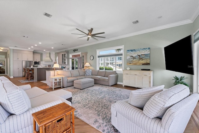 living room featuring crown molding, ceiling fan, and light hardwood / wood-style floors