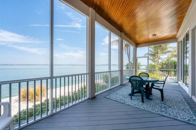 sunroom featuring a beach view and a water view