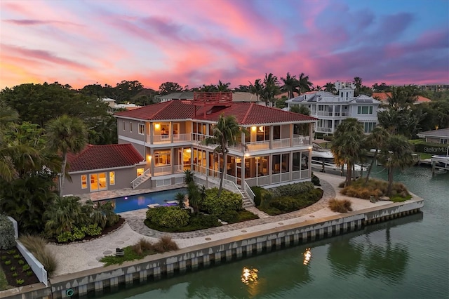 back house at dusk with a balcony and a water view