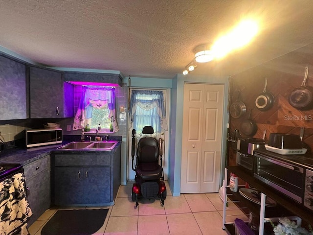 kitchen with light tile patterned floors, a textured ceiling, black electric range oven, and sink