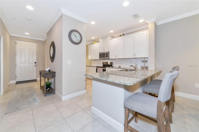 kitchen featuring a kitchen bar, appliances with stainless steel finishes, crown molding, sink, and white cabinets