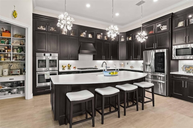 kitchen with pendant lighting, an island with sink, stainless steel appliances, and custom range hood