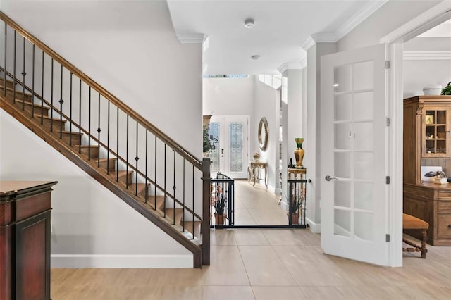 entrance foyer featuring light tile patterned floors, ornamental molding, and french doors