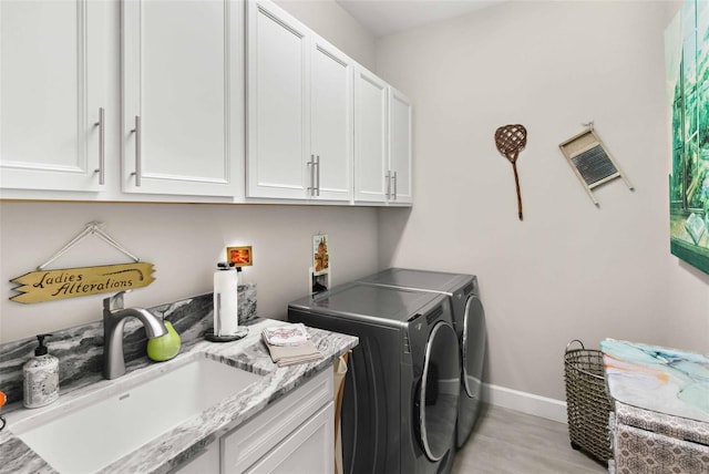 clothes washing area with cabinets, sink, and washer and dryer