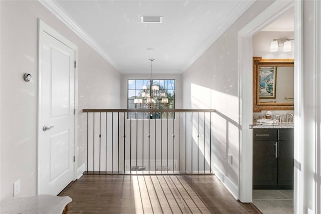 hallway with dark hardwood / wood-style flooring, ornamental molding, and an inviting chandelier