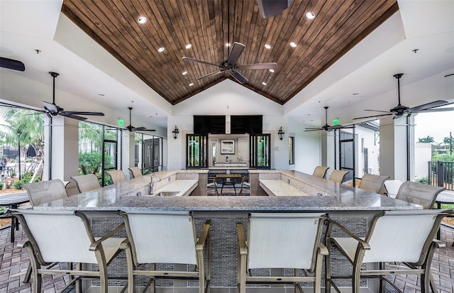 kitchen featuring wooden ceiling, light stone counters, and a breakfast bar area