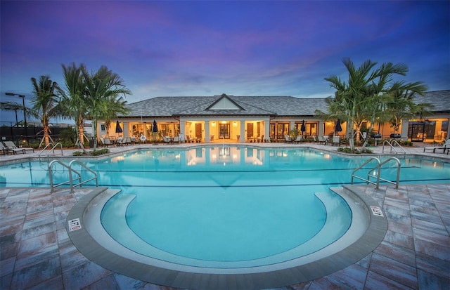 pool at dusk featuring a patio area