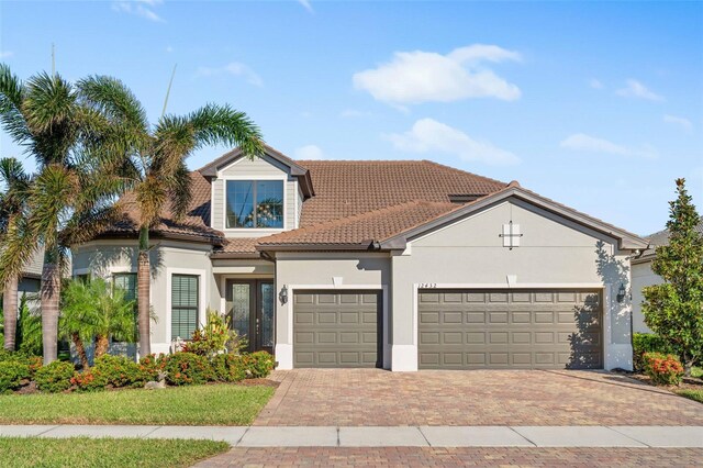 view of front of property featuring decorative driveway, stucco siding, an attached garage, and a tiled roof