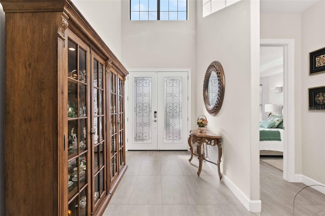 tiled entrance foyer featuring a high ceiling, french doors, and baseboards