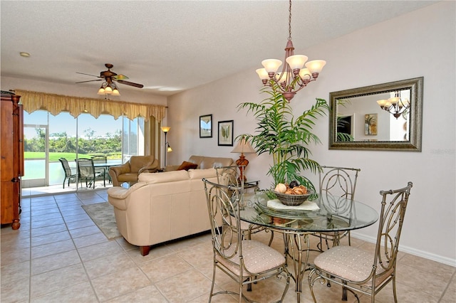 tiled dining area with a textured ceiling and ceiling fan with notable chandelier