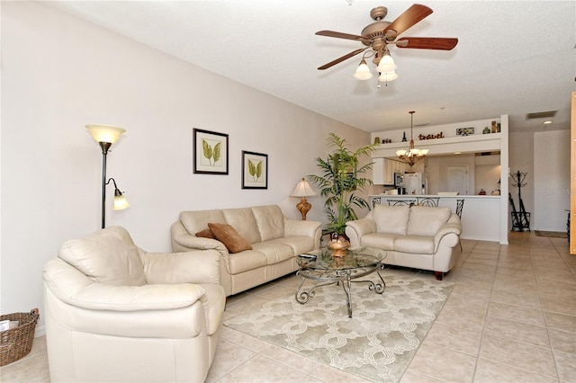 living room featuring ceiling fan with notable chandelier, light tile patterned floors, and a textured ceiling