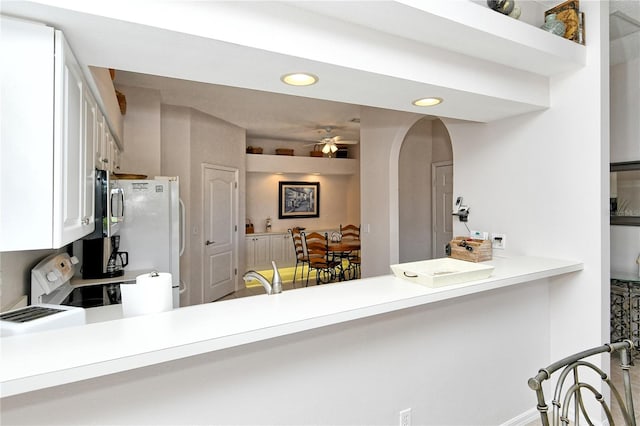 kitchen featuring kitchen peninsula, white appliances, ceiling fan, sink, and white cabinets