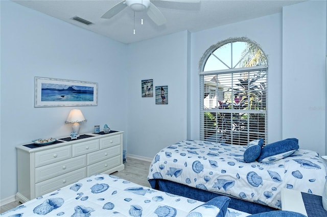 bedroom with ceiling fan, light hardwood / wood-style flooring, and a textured ceiling