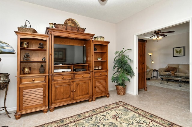 living room featuring a textured ceiling, ceiling fan, and light tile patterned flooring