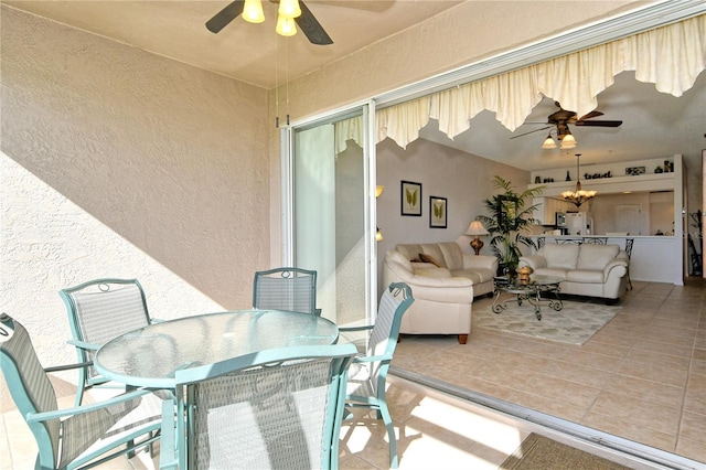 sunroom / solarium featuring ceiling fan with notable chandelier