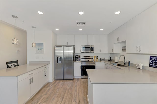 kitchen featuring kitchen peninsula, sink, hanging light fixtures, and appliances with stainless steel finishes