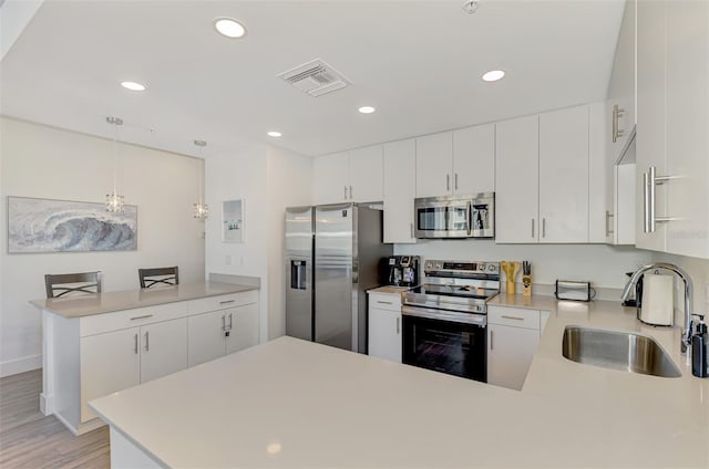 kitchen with white cabinets, sink, hanging light fixtures, kitchen peninsula, and stainless steel appliances