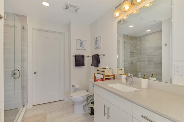 bathroom featuring vanity, a shower with shower door, and toilet