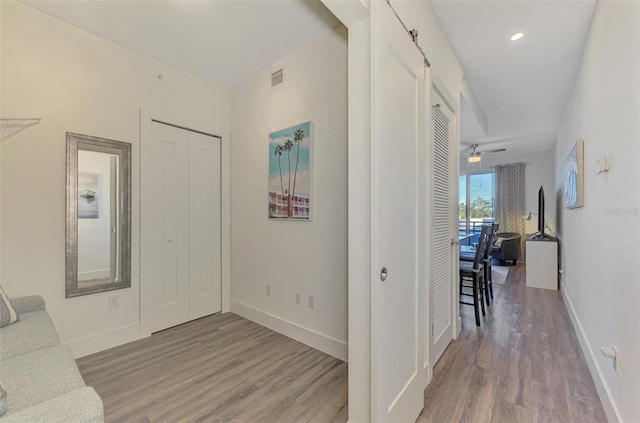 foyer entrance featuring a barn door, hardwood / wood-style flooring, and ceiling fan