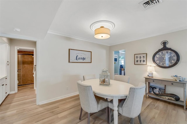 dining space featuring crown molding and light hardwood / wood-style flooring