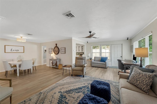 living room with light wood-type flooring, ceiling fan, and crown molding