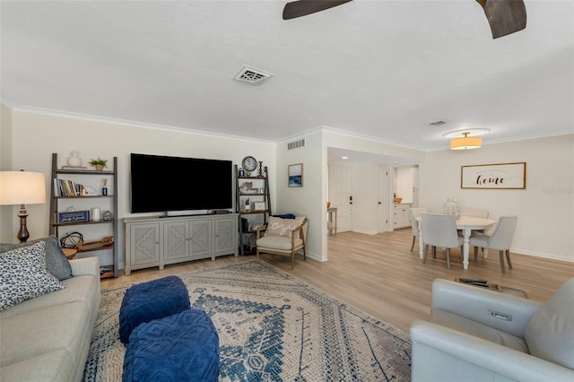 living room with ceiling fan, light wood-type flooring, and ornamental molding