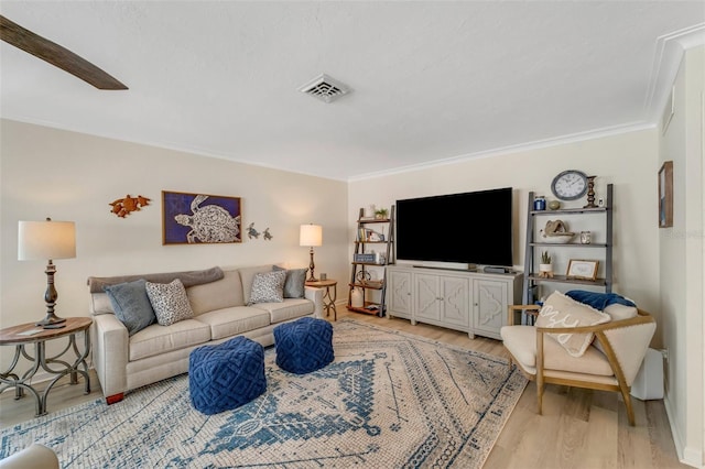 living room with crown molding, ceiling fan, and light wood-type flooring