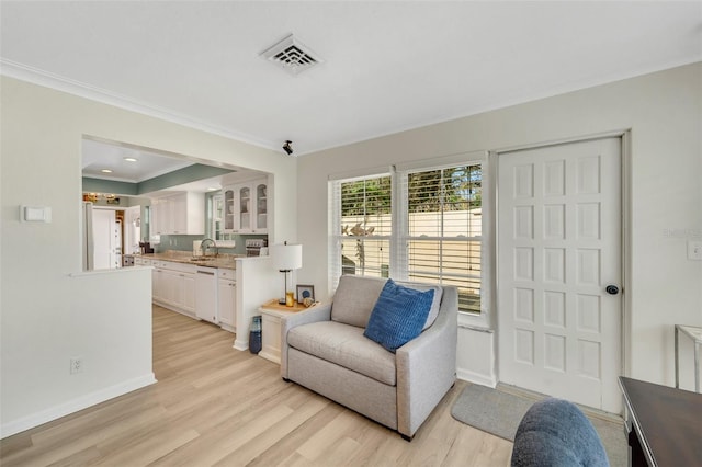 living area with light hardwood / wood-style floors, ornamental molding, and sink