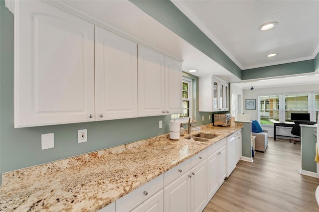 kitchen with white cabinets, white dishwasher, light stone countertops, and sink