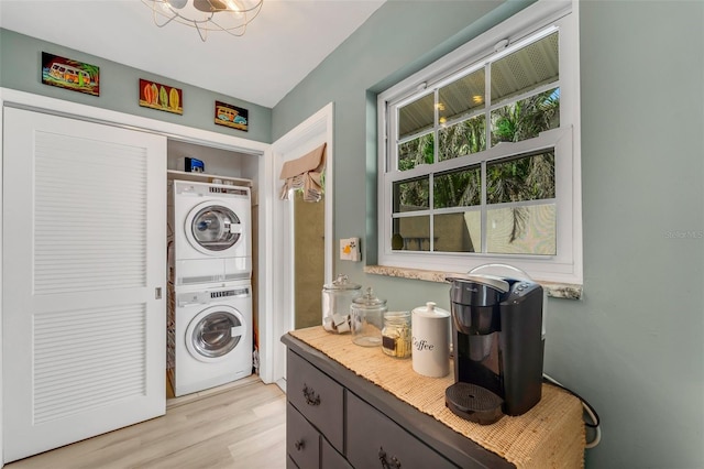 laundry room with light wood-type flooring and stacked washer and dryer