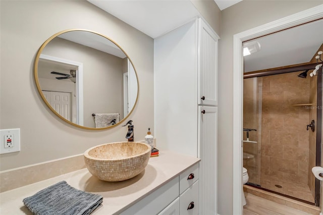 bathroom featuring ceiling fan, toilet, walk in shower, and vanity