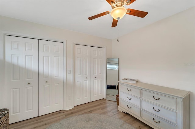 bedroom featuring two closets, ceiling fan, and light hardwood / wood-style floors