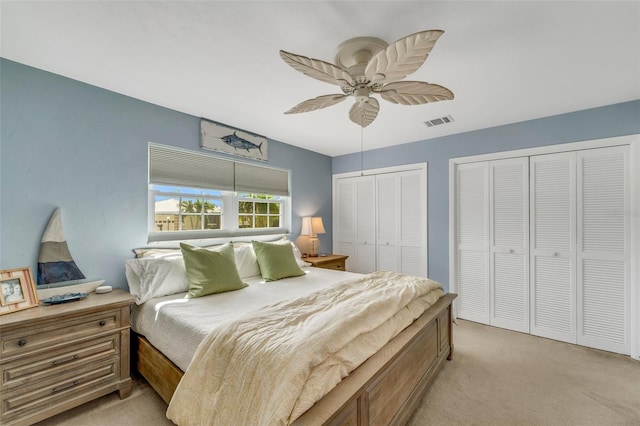 bedroom featuring multiple closets, ceiling fan, and light carpet