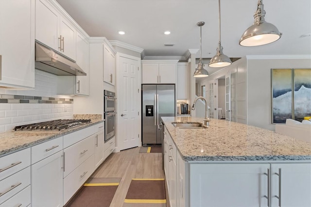 kitchen with pendant lighting, a center island with sink, sink, appliances with stainless steel finishes, and white cabinetry