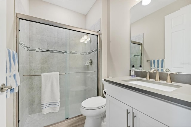 bathroom with wood-type flooring, vanity, toilet, and walk in shower