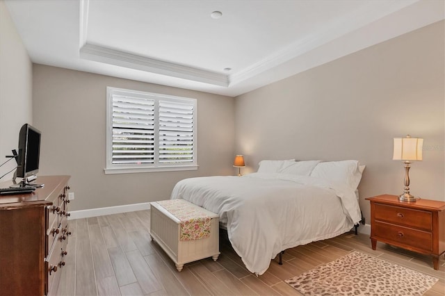 bedroom with a raised ceiling and light hardwood / wood-style flooring