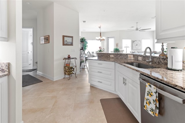 kitchen featuring stainless steel dishwasher, sink, decorative light fixtures, stone counters, and white cabinetry