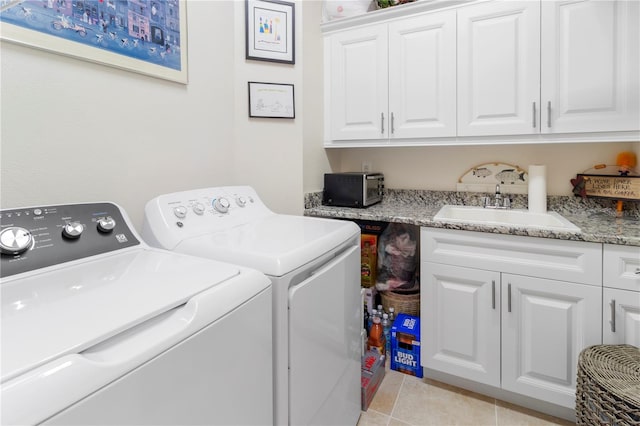 laundry room with washing machine and dryer, sink, light tile patterned floors, and cabinets