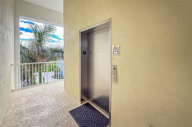 view of exterior entry featuring elevator and a balcony