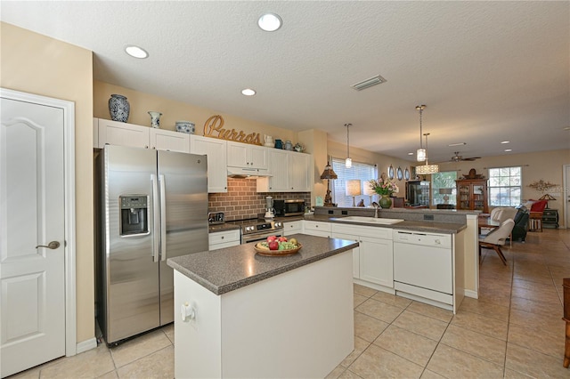 kitchen featuring sink, appliances with stainless steel finishes, decorative light fixtures, a kitchen island, and kitchen peninsula