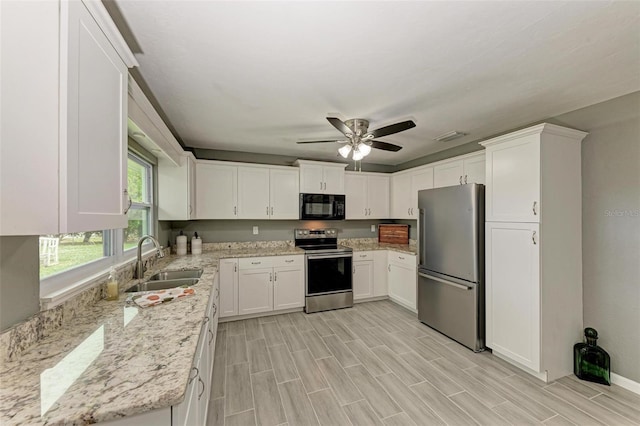 kitchen featuring sink, light hardwood / wood-style flooring, light stone countertops, white cabinetry, and stainless steel appliances