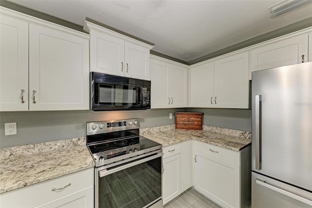 kitchen with light stone countertops, white cabinetry, and stainless steel appliances