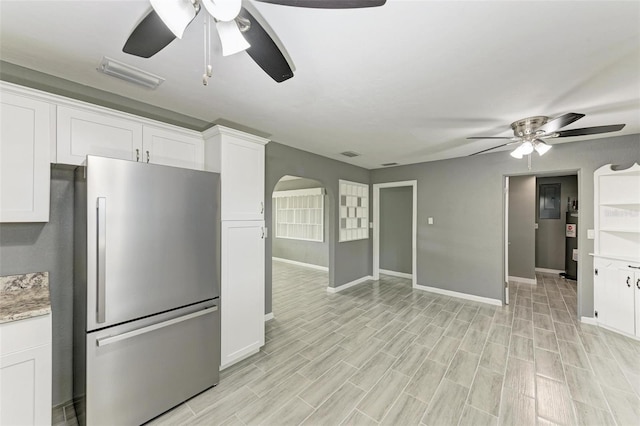 kitchen with white cabinets, ceiling fan, stainless steel fridge, and light hardwood / wood-style floors