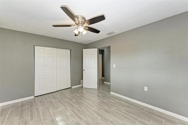 unfurnished bedroom with ceiling fan, light wood-type flooring, a textured ceiling, and a closet